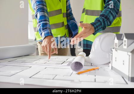 Ingenieure und Architekten stehen auf einer Baustelle mit architektonischem Plan und lächelndem Lächeln Stockfoto