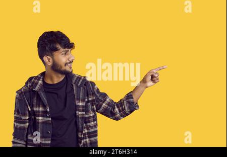 Glücklicher positiver junger indianer, der mit Fingerhand auf den Kopierraum zeigt. Stockfoto