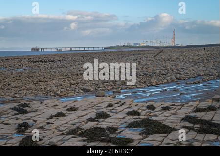 Hinkley Point Baustelle hinter Kalksteinpflastern und Felsbrocken, die bei Ebbe an der Somerset Coast bei Lilstock, Somerset, England, Großbritannien, Stockfoto