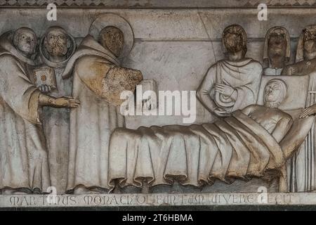 Eines der romanischen Reliefs aus dem 13. Jahrhundert von „Storie di San Martino“ an der Fassade des Duomo di San Martino, Lucca, Toskana, Italien. Die Reliefs, die Szenen aus dem Leben des heiligen Martin von Tours darstellen, können das Werk des lombardischen Bildhauers Guido oder Guidetto di Bonagiunta Bigarelli sein, bekannt als Guido da Como (1220–ca. 1257). Stockfoto