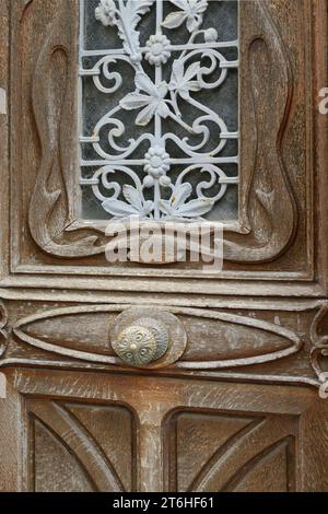 Alte Holztür mit verziertem Messingknauf und bemalter Blumenschmuck, Schmiedearbeiten, die das Glasfenster bedecken, Honfleur, Calvados, Basse Normandie, Stockfoto