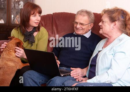 Helfen Sie älteren Menschen: Eltern besuchen. Eine reife Frau besucht ihre alternden Eltern mit ihrem Hund zu Hause. Aus einer Reihe verwandter Bilder. Stockfoto