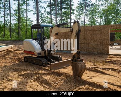 Minibagger parkte auf dem Boden vor einem neuen Wohnbauprojekt auf einer Baustelle. Stockfoto