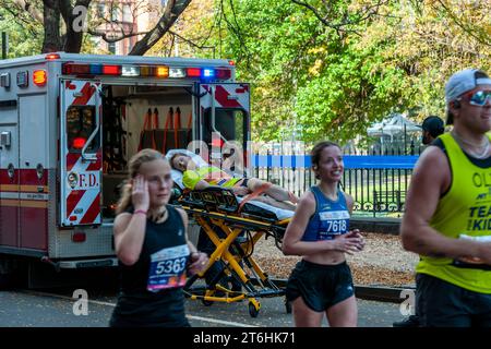 EMT-Läufer laden einen Läufer in ihren Krankenwagen, während die Läufer beim TCS New York City Marathon am Sonntag, den 5. November 2023, in der Nähe der 22-Meilen-Marke in der Nähe des Mount Morris Park durch Harlem in New York fahren. (© Richard B. Levine) Stockfoto