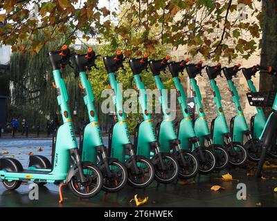 Reihe von hellgrünen West Scoot Elektrorollern, betrieben von der deutschen Firma Tier in James Street West, Bath, Somerset. Stockfoto