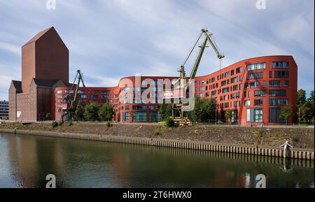 Duisburg, Ruhrgebiet, Nordrhein-Westfalen, Deutschland - Duisburger Innenhafen mit dem wellenförmigen Neubau des Landesarchivs Nordrhein-Westfalen, dem wiederaufgebauten Archivturm im ehemaligen RWSG-Lagergebäude und alten Hafenkränen. Stockfoto