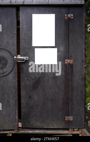 Zwei leere Plakate an der Tür eines alten Sperrholzschuppen im Wald. Stockfoto