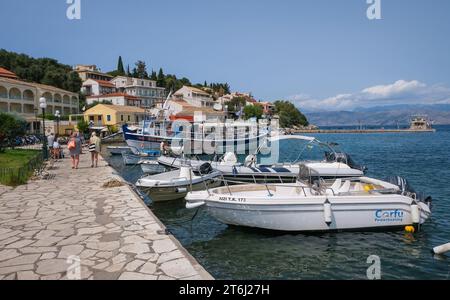 Kassiopi, Korfu, Griechenland, Fischerboote und ein Ausflugsboot im Hafen von Kassiopi, einer kleinen Hafenstadt im Nordosten der griechischen Insel Korfu, hinten rechts an der Küste Albaniens auf Höhe der Stadt Saranda. Stockfoto