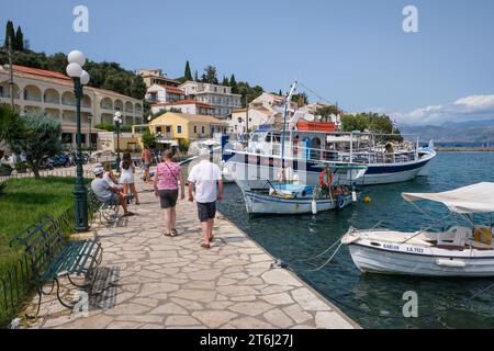 Kassiopi, Korfu, Griechenland, Fischerboote und ein Ausflugsboot im Hafen von Kassiopi, einer kleinen Hafenstadt im Nordosten der griechischen Insel Korfu, hinten rechts an der Küste Albaniens auf Höhe der Stadt Saranda. Stockfoto