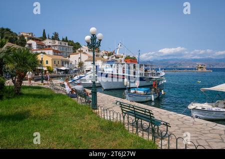 Kassiopi, Korfu, Griechenland, Fischerboote und ein Ausflugsboot im Hafen von Kassiopi, einer kleinen Hafenstadt im Nordosten der griechischen Insel Korfu, hinten rechts an der Küste Albaniens auf Höhe der Stadt Saranda. Stockfoto