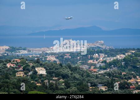 Korfu Stadt, Korfu, Griechenland, Stadtübersicht Korfu. TUI Flugzeug startet vom Flughafen Korfu und fliegt über die Stadt, im Hintergrund das Festland Albaniens. Stockfoto