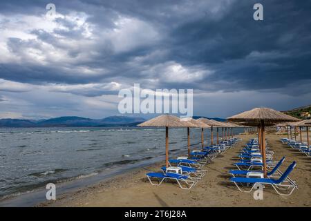 Kalamaki, Korfu, Griechenland, Sonnenliegen und Sonnenschirme am Kalamaki Strand im Nordosten der griechischen Insel Korfu, im Hintergrund das Festland Albaniens Stockfoto