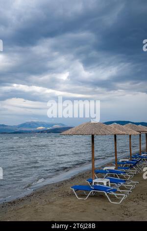 Kalamaki, Korfu, Griechenland, Sonnenliegen und Sonnenschirme am Kalamaki Strand im Nordosten der griechischen Insel Korfu, im Hintergrund das Festland Albaniens Stockfoto