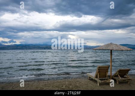 Kalamaki, Korfu, Griechenland, Sonnenliegen und Sonnenschirme am Kalamaki Strand im Nordosten der griechischen Insel Korfu, im Hintergrund das Festland Albaniens mit dem Badeort Saranda. Stockfoto