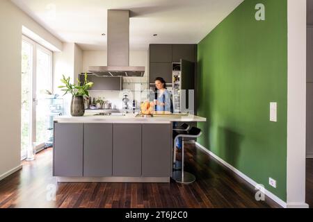 Frau in einer modernen Wohnung mit Küchenbereich, Stockfoto
