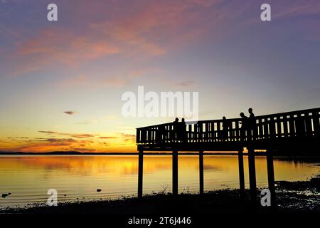 Deutschland, Bayern, Oberbayern, Landkreis Traunstein, Chieming, Chiemsee, Sonnenuntergang, Steg, Leute, Silhouette Stockfoto