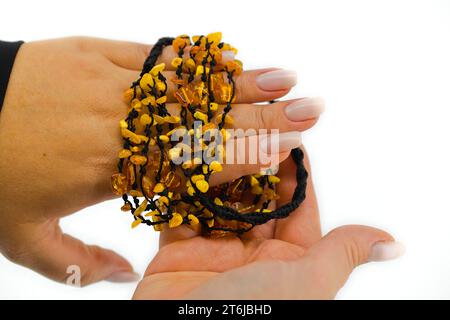 Das Bild zeigt eine polierte braune Halskette auf einer schwarzen Kordel, die zart in femininen Händen gehalten wird. Die goldenen Farbtöne stehen im Kontrast zum Schwarz. Stockfoto