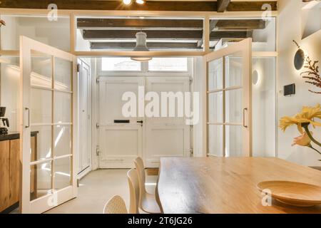 Eine Küche und Essbereich in einem winzigen Haus mit weißen Wänden, Holzfußboden und freiliegendem Deckenventilator an der Wand Stockfoto