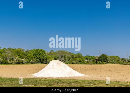 Großer Haufen weißes Material, das auf ein neu gepflügtes Feld geworfen wird Stockfoto