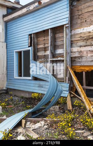 Teilweise abgerissenes Gebäude mit blauer Vinylverkleidung. Stockfoto
