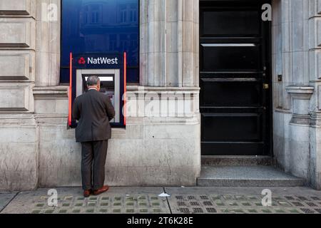 Ein Mann benutzt einen Geldautomat der National Westminster Bank in einer Straße nahe dem Piccadilly Circus in London. UK Stockfoto