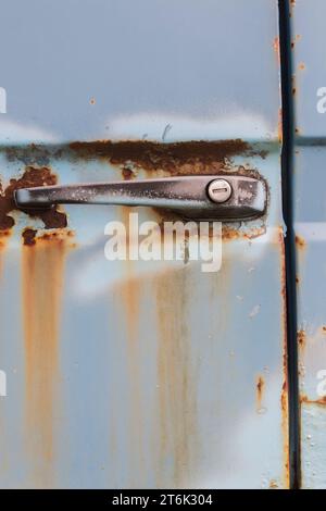 Roststellen und Griff mit Schlüsselloch an der Tür des alten blauen Lkws. Stockfoto