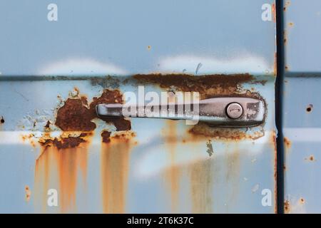 Roststellen und Griff mit Schlüsselloch an der Tür des alten blauen Lkws. Stockfoto