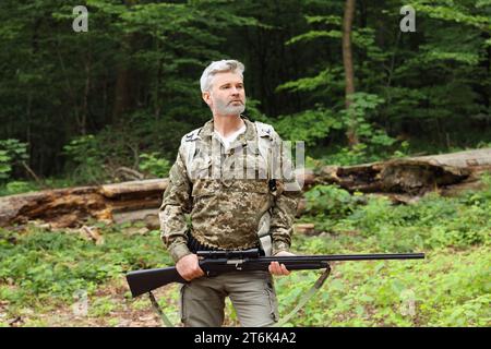 Mann mit Jagdgewehr und Rucksack in Tarnung im Wald Stockfoto