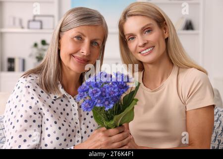 Glückliche reife Mutter und Tochter mit schönen Kornblumen zu Hause Stockfoto