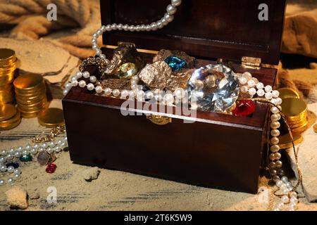 Truhe mit Schätzen und verstreutem Sand auf dem Boden Stockfoto