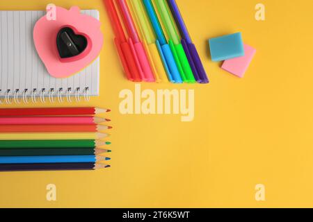 Flache Laienzusammenstellung mit verschiedenen Schreibwaren auf gelbem Hintergrund, Platz für Text. Zurück in die Schule Stockfoto