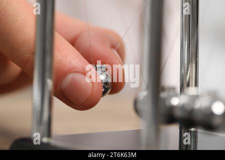 Mann, der mit Newtons Wiege spielt, Nahaufnahme. Physikalisches Gesetz der Energieeinsparung Stockfoto