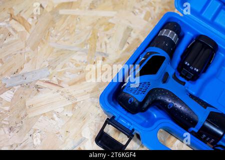 Roter Elektrobohrer liegt in einem dunklen Koffer auf einem Holztisch Stockfoto