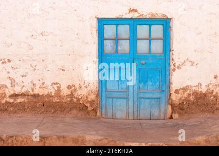 Blaue Doppeltür mit quadratischen Fenstern in einem Gebäude in San Pedro de Atacama, Chile. Stockfoto