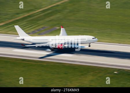 Kommerzielles Flugzeug landet an sonnigem Tag auf der Start- und Landebahn des Flughafens. Flugzeug mit Rauch hinter den Rädern beim Bremsen. Stockfoto