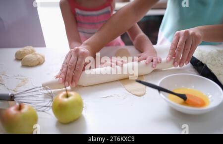 Mama und Tochter Rollen den Teig mit Nudelholz in der Küche aus Stockfoto