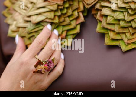 Nahaufnahme des Halsschmucks einer Frau aus grünen Blättern und einem Ring an ihrer Hand. Der Begriff der Floristik. Stockfoto