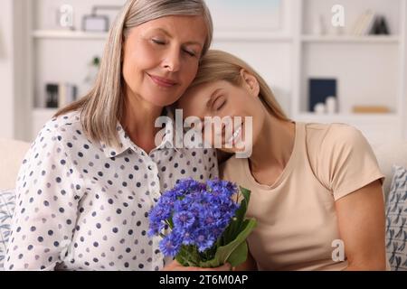 Glückliche reife Mutter und Tochter mit schönen Kornblumen zu Hause Stockfoto