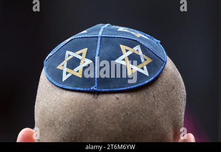 9. November 2023, Brandenburg, Potsdam: Ein Mann trägt eine blaue Kippah mit gelben und weißen Davidsternen auf dem Kopf, aufgenommen auf dem Jüdischen Friedhof in Potsdam. Foto: Soeren Stache/dpa Stockfoto