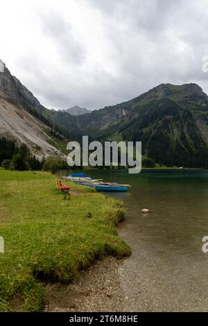 Bergsee in den österreichischen alpen mit Booten darauf und roter Bank davor Stockfoto