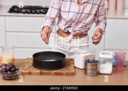 Weibliche Hände bereiten Kuchen in der modernen Küche vor, Frau fügt Zutaten in die Schüssel Stockfoto