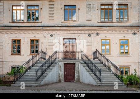 Treppe mit schmiedeeisernen Metallgeländern. Eingangsgruppe in Villa und schäbiger Fassade. Erspart das Anwesen in Lettland, Baltikum. Stockfoto