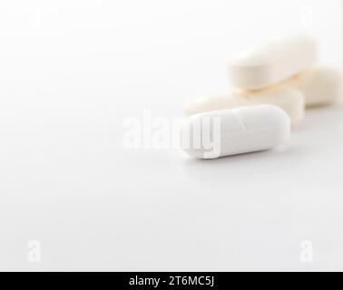 Nahaufnahme einer weißen Pille oder Kapseln auf weißem Tisch. Stockfoto