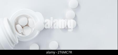 Apothekenthema, Flasche und verstreute weiße runde Tabletten auf dem Tisch, Blick von oben, flache Lage. Stockfoto