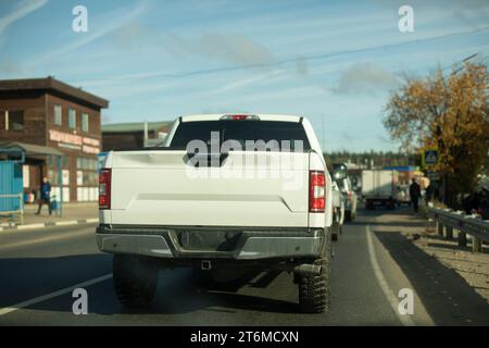 Der weiße Pickup fährt die Straße runter. Lkw auf der Straße. Karosserie. Frachttransport. Stockfoto