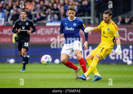 11. November 2023, Schleswig-Holstein, Kiel: Fußball: Bundesliga 2, Holstein Kiel - Hamburger SV, Spieltag 13, Holstein Stadium. Kiels Benedikt Pichler (Mitte) und Hamburger Torhüter Daniel Heuer Fernandes (rechts) kämpfen um den Ball. Foto: Axel Heimken/dpa - WICHTIGER HINWEIS: Gemäß den Vorschriften der DFL Deutschen Fußball-Liga und des DFB Deutschen Fußball-Bundes ist es verboten, im Stadion und/oder des Spiels aufgenommene Fotografien in Form von sequenziellen Bildern und/oder videoähnlichen Fotoserien zu verwenden oder zu nutzen. Stockfoto