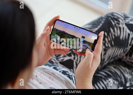 Minecraft mobiles iOS-Spiel auf dem iPhone 15 Smartphone-Bildschirm in weiblichen Händen während des mobilen Gameplays. Mobiles Gaming und Entertainment auf einem tragbaren Gerät Stockfoto