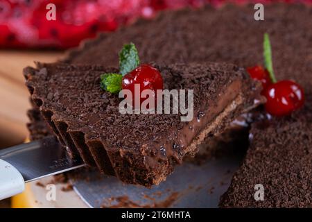 Ein Stück aus dunkler Schokoladenkuche, dekoriert mit Kirsch. Stockfoto