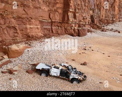 Sidmouth, Devon, Großbritannien. November 2023. Sidmouth Independent Lifeboat Crew wurde vor ein paar Wochen beim Sturm Ciaran gerufen, um eine Person in seinem Auto zu retten. Das Auto war auf der Hangbahn und rollte ins Meer. Die Person wurde gerettet, aber das Auto wurde ins Meer gespült. Einige Tage später wird das Auto unter der Red Cliff Face am Strand an der Jurassic Coast Line in Sidmouth East Devon gesehen. Bildnachweis Robert Timoney/Alamy/Live/News Stockfoto