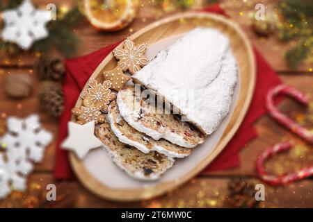 Traditioneller Weihnachtsstollen mit Puderzucker auf Holztisch, flach gelegt. Bokeh-Effekt Stockfoto